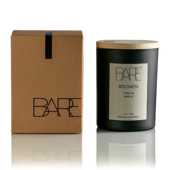 White background. Recycable brown box with Bare logo on the left side. Next to it, on the right side, Boldness, scented candle in a closed black jar with beige label on it.