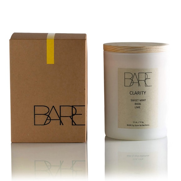 White background. Recycable brown box with Bare logo on the left side. Next to it, on the right side, Clarity scented candle in a closed white jar with beige label on it that says BARE, Sweet Mint, Basil, Lime.